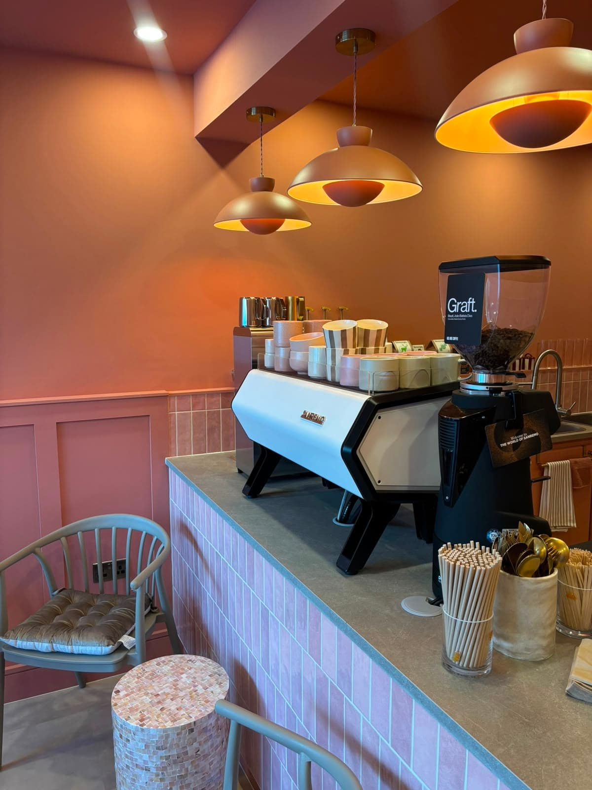 The counter at Sister Coffee, copper pendant lights hanging over pink tiles and the espresso machine