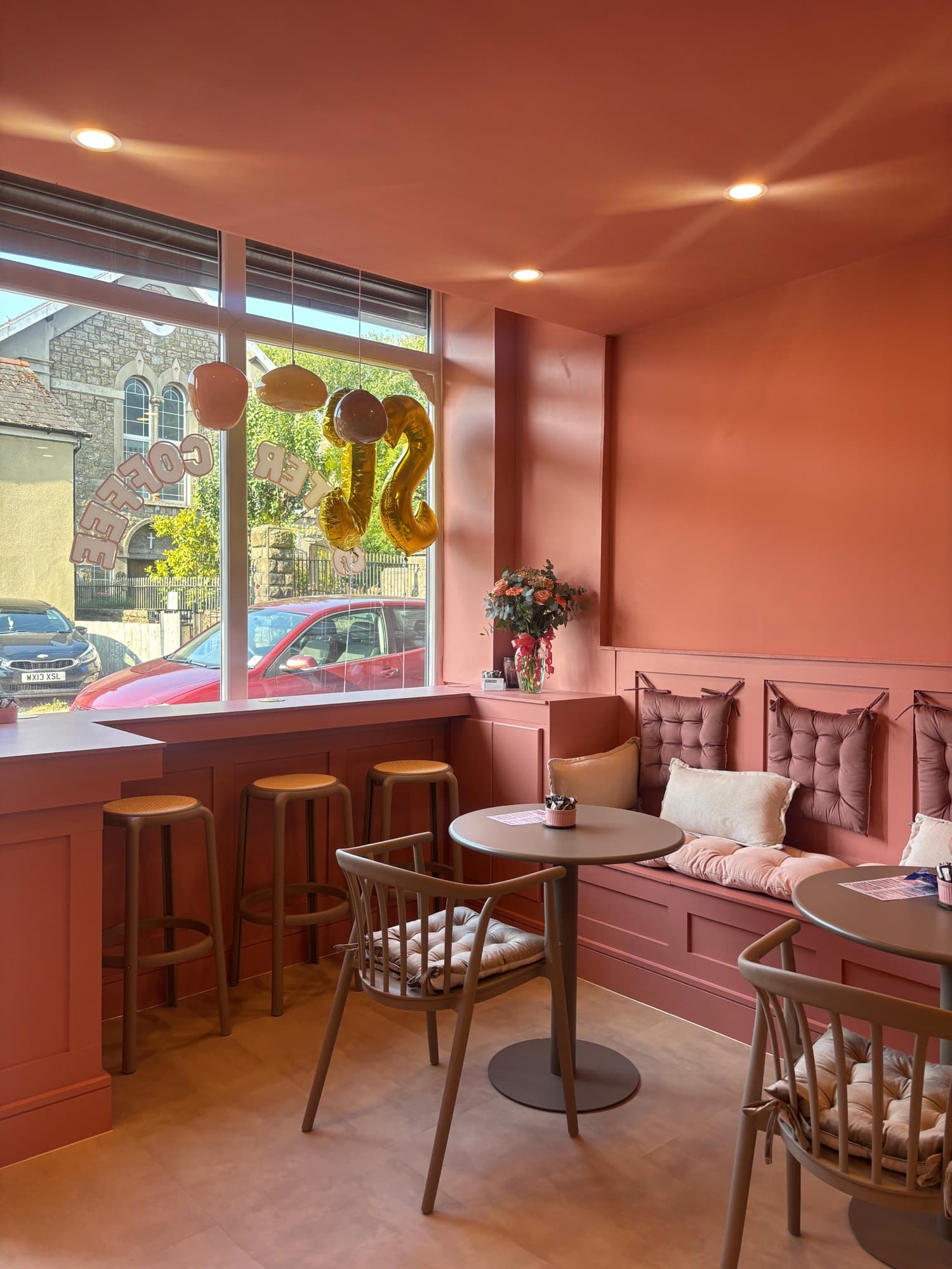 Tables, chairs and bench seating looking out of the front window of Sister Coffee onto the street